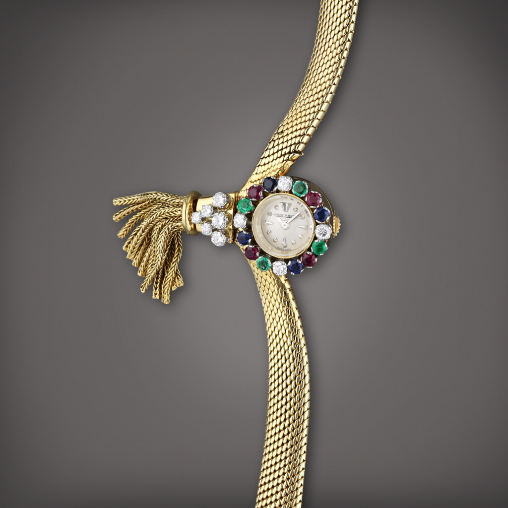 View full screen - View 1 of Lot 98. Reference 7368 | A yellow gold and diamond, emerald, ruby, and sapphire-set bracelet watch with decorative tassel, Made in 1959.