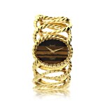 REFERENCE 9855 D35 RETAILED BY VAN CLEEF & ARPELS: A YELLOW GOLD CUFF WATCH WITH TIGER'S EYE DIAL, CIRCA 1970