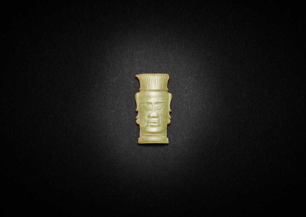 View full screen - View 1 of Lot 3794. A Shijiahe type pale celadon jade 'human face' plaque, Early Western Zhou dynasty | 西周早期 石家河類型淺青黃玉人面形飾.