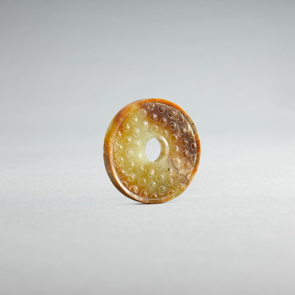 View full screen - View 1 of Lot 734. A small pale-celadon jade disc, bi, Eastern Zhou dynasty, Spring and Autumn period | 東周春秋 青白玉榖紋璧.