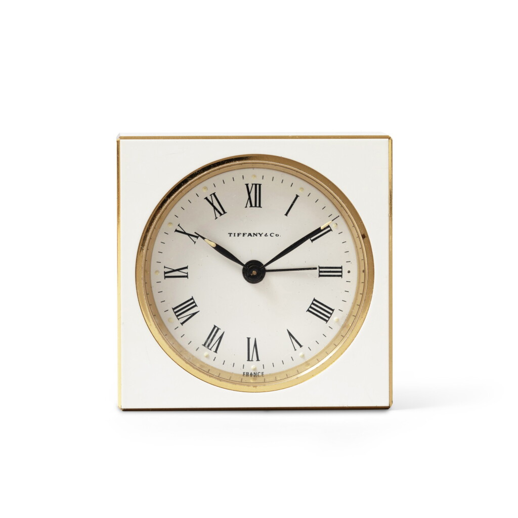 View full screen - View 1 of Lot 370. Tiffany & Co, New York A modern gilt brass and white enamel alarm travelling time piece | Ein moderner Wecker aus Messing und weißem Lack, nummeriert 71-1-424, Uhrwerk nicht funktionstüchtig.