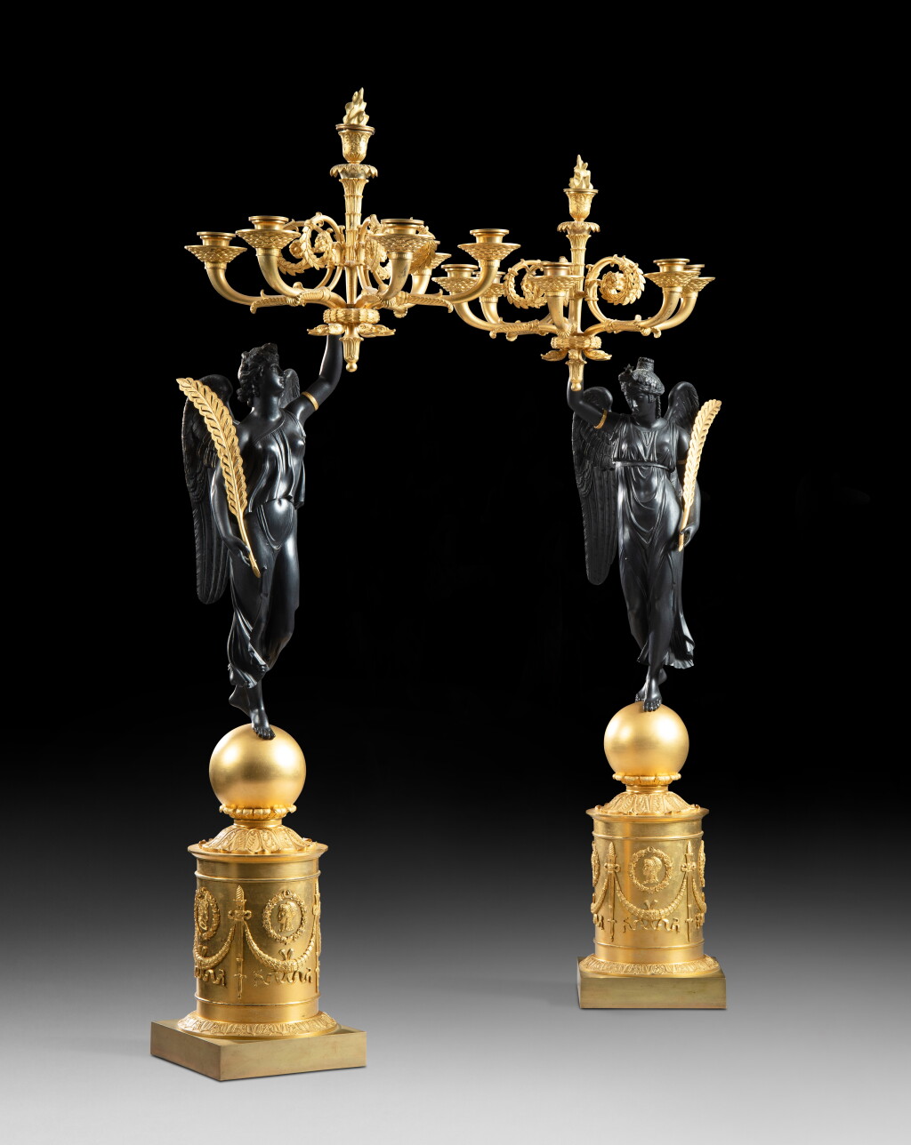 View full screen - View 1 of Lot 17. A pair of patinated and gilt-bronze six-light candelabra, Empire, circa 1810, attributed to Pierre-Philippe Thomire | Paire de candélabres aux Renommées à six lumières en bronze patiné et doré d'époque Empire, vers 1810, attribuée à Pierre-Philippe Thomire.