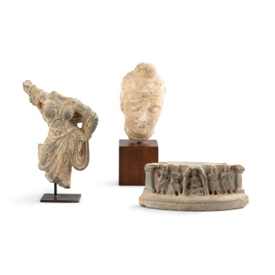 View full screen - View 1 of Lot 1058. A group of two limestone carvings and a stucco head of a deity, ancient region of Gandhara, 2nd – 3rd century | Ensemble de deux reliefs en pierre calcaire sculptée et une tête de divinité en stuc, ancienne région du Gandhara, IIe - IIIe siècle .