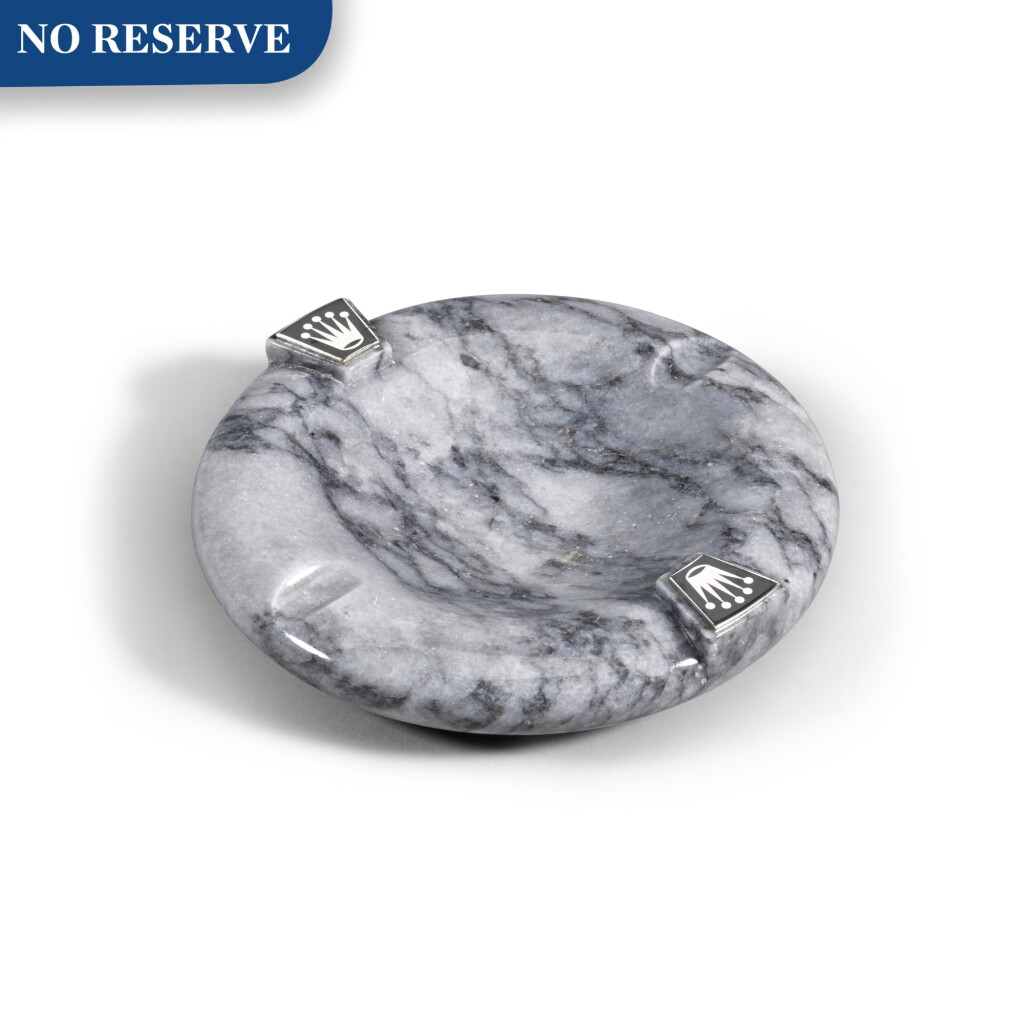 View full screen - View 1 of Lot 718. REFERENCE RMA 210-G GREY MARBLE ROUND ASHTRAY WITH APPLIED ROLEX CORONET EMBLEMS, BAIZE UNDERSIDE CIRCA 1970.