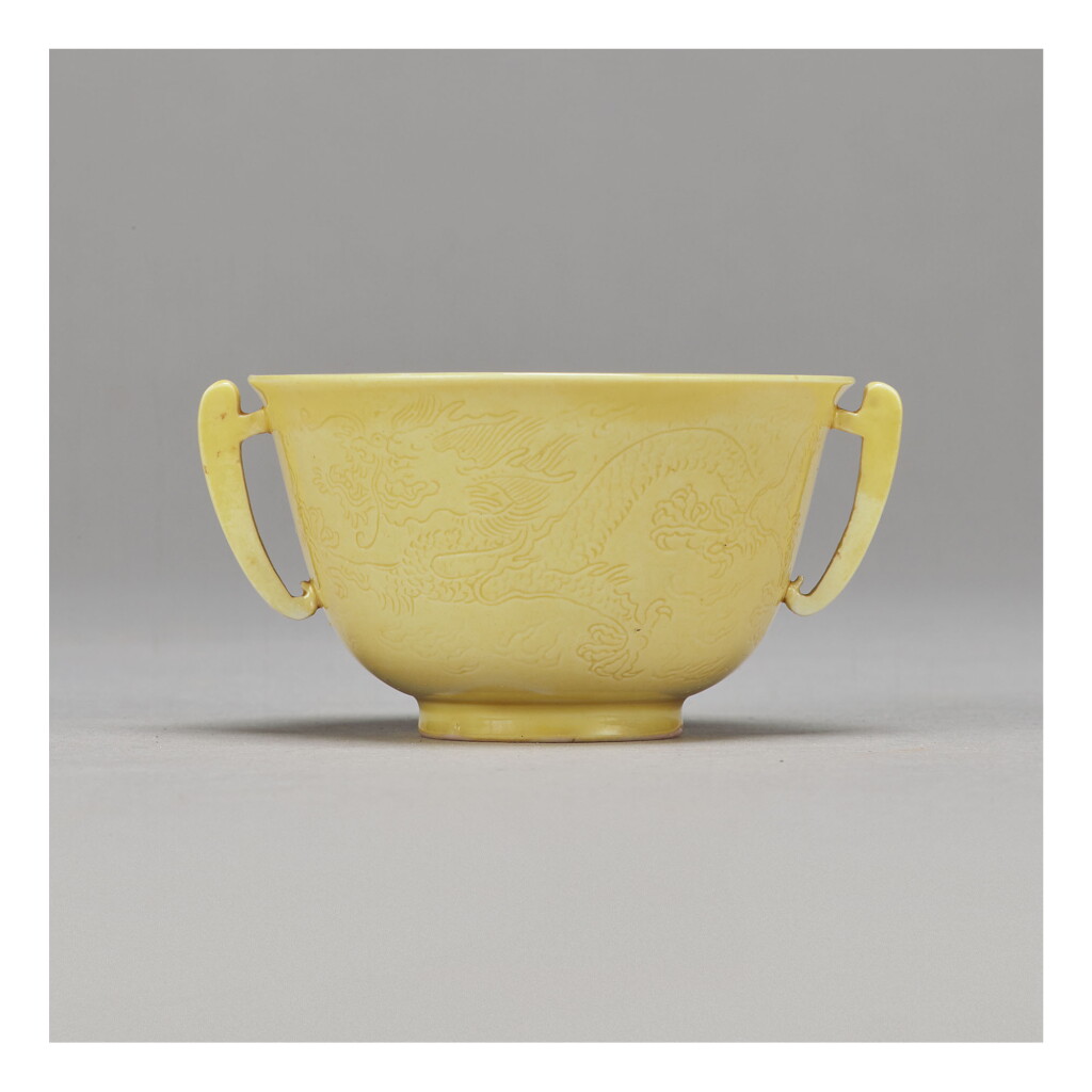 View full screen - View 1 of Lot 101. A FINE INCISED YELLOW-GLAZED 'DRAGON' HANDLED CUP, KANGXI MARK AND PERIOD.