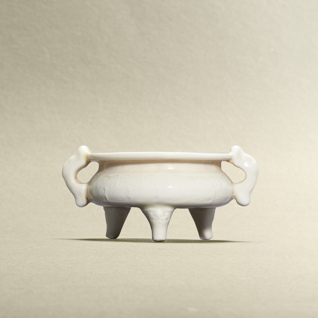 View full screen - View 1 of Lot 5770. A blanc-de-Chine archaistic handled tripod incense burner, Lin Jiesheng mark, Qing dynasty, 19th century | 清十九世紀 德化白釉仿古紋雙魚耳三足爐 《林捷陞製》.