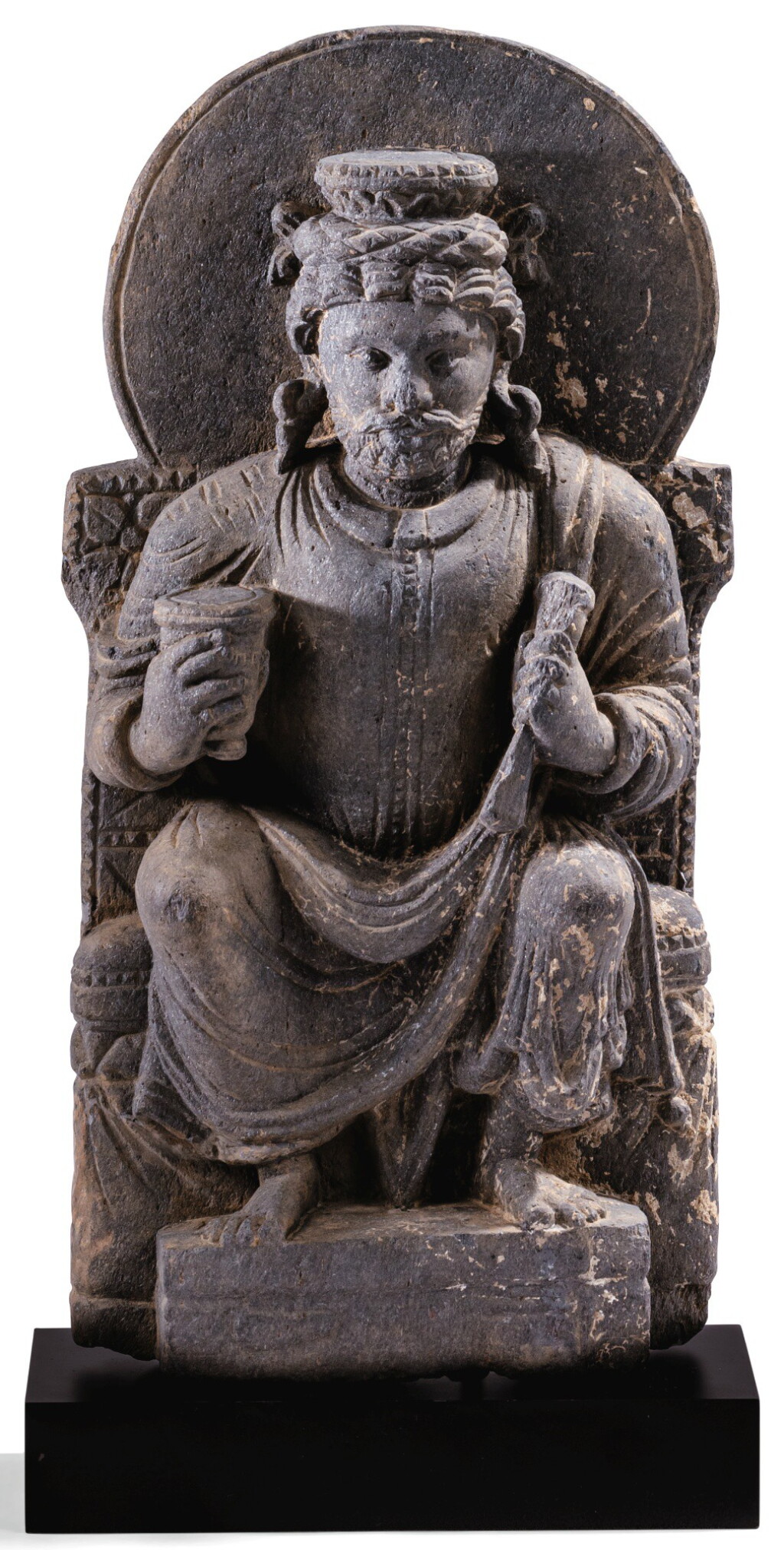 View full screen - View 1 of Lot 140. STATUETTE D'INDRA EN SCHISTE GRIS GANDHÂRA, IIE-IVE SIÈCLE | 犍陀羅 二至四世紀 灰片岩雕因陀羅坐像 | A grey schist figure of seated Indra, Gandhara, 2nd/4th century.