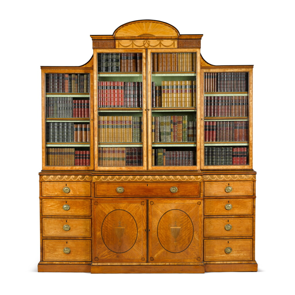 View full screen - View 1 of Lot 203. A George III satinwood, amaranth and marquetry breakfront bookcase, circa 1770, attributed to Mayhew & Ince.