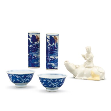 View full screen - View 1 of Lot 342. A PAIR OF BLUE AND WHITE CUPS, A PAIR OF TAPER HOLDERS AND A DEHUA 'BOY ON BUFFALO' WATERPOT QING DYNASTY | 清 青花梅花紋小盃一對、青花釉裏紅山水人物圖花插一對 及 德化白釉臥牛童子水丞.