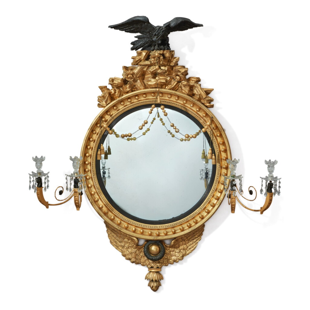 View full screen - View 1 of Lot 703. A REGENCY GILTWOOD AND EBONISED CONVEX GIRANDOLE MIRROR WITH A PAIR OF TWO-LIGHT CANDLE ARMS, EARLY 19TH CENTURY.