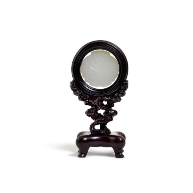 View full screen - View 1 of Lot 111. A small white jade circular 'boy' plaque on a carved wood stand Qing dynasty, 18th/19th century | 清十八/十九世紀 白玉童子珮.