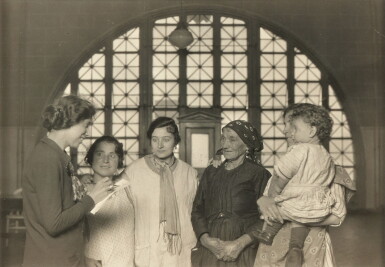 View full screen - View 1 of Lot 962. Ellis Island, Welfare worker gathers data from immigrants detained.