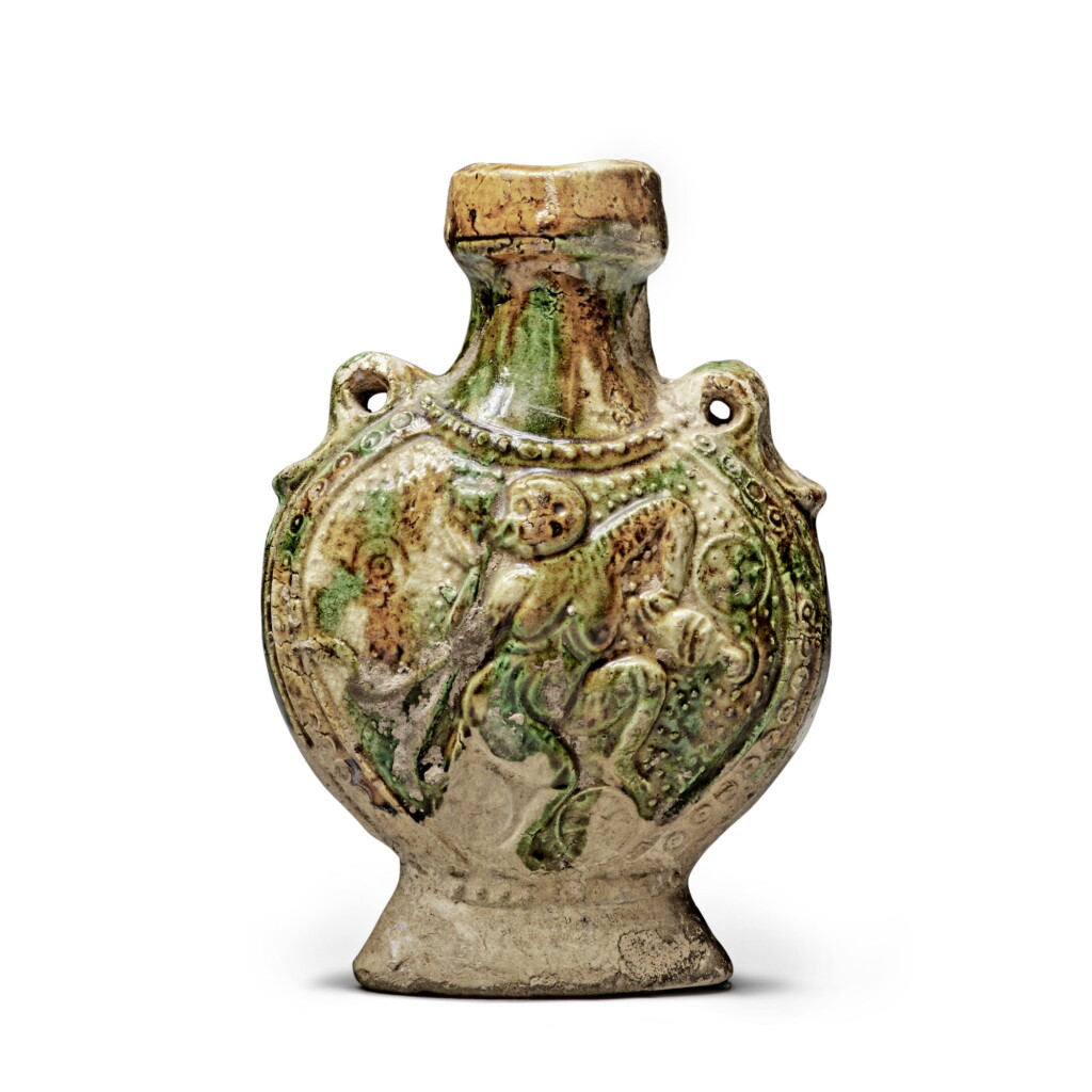 View full screen - View 1 of Lot 92. A molded sancai-glazed pottery pilgrim flask, Tang dynasty | 唐 三彩模印樂舞圖雙繫扁壺.