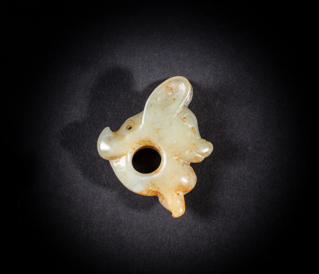 View full screen - View 1 of Lot 77. A rare and unusual celadon and russet jade ‘pig dragon’ pendant (Zhulong), Neolithic period, Hongshan culture | 新石器時代紅山文化 青白玉豬龍.