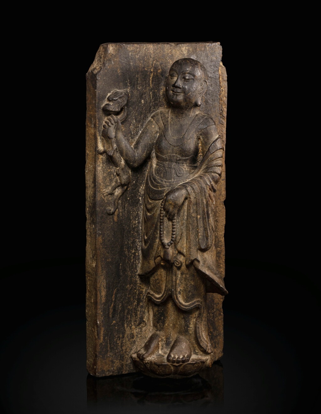 View full screen - View 1 of Lot 51. A rare limestone carving of a Buddhist acolyte, possibly Jianglong Luohan Northern Song dynasty, 10th-11th century | 北宋十至十一世紀 石灰石浮雕或為降龍羅漢像.