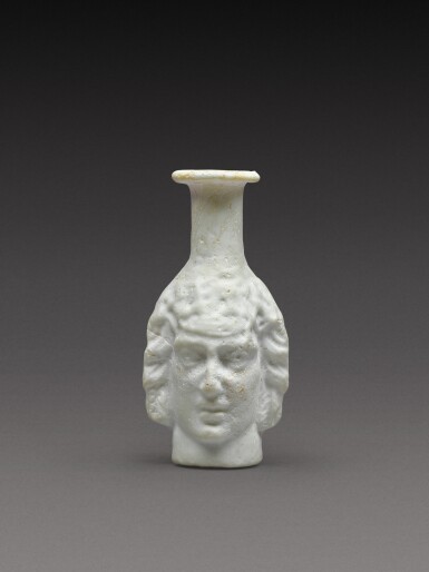 View full screen - View 1 of Lot 2. A Roman Opaque White Mould-Blown Janiform Glass Flask, circa 1st/2nd century AD.
