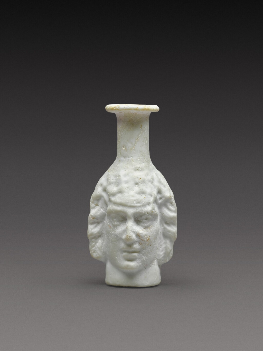 View full screen - View 1 of Lot 2. A Roman Opaque White Mould-Blown Janiform Glass Flask, circa 1st/2nd century AD.