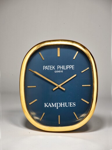 View full screen - View 1 of Lot 110. PATEK PHILIPPE | ELLIPSE RETAILED BY KAMPHUES: A LARGE GILT BRASS OVAL FORM WALL CLOCK, CIRCA 1990.