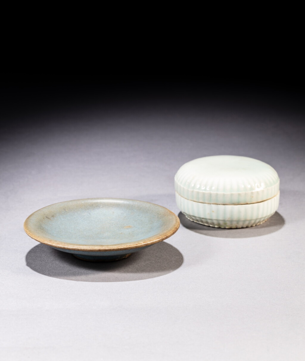 View full screen - View 1 of Lot 75. A small Qingbai 'chrysanthemum' lobed box and cover and a 'Jun' blue-glazed saucer, Song / Yuan dynasty | 宋 / 元 白釉堆花卉紋竹節花式小蓋盒及鈞窰天藍釉小盤 《吳家合子記》款.