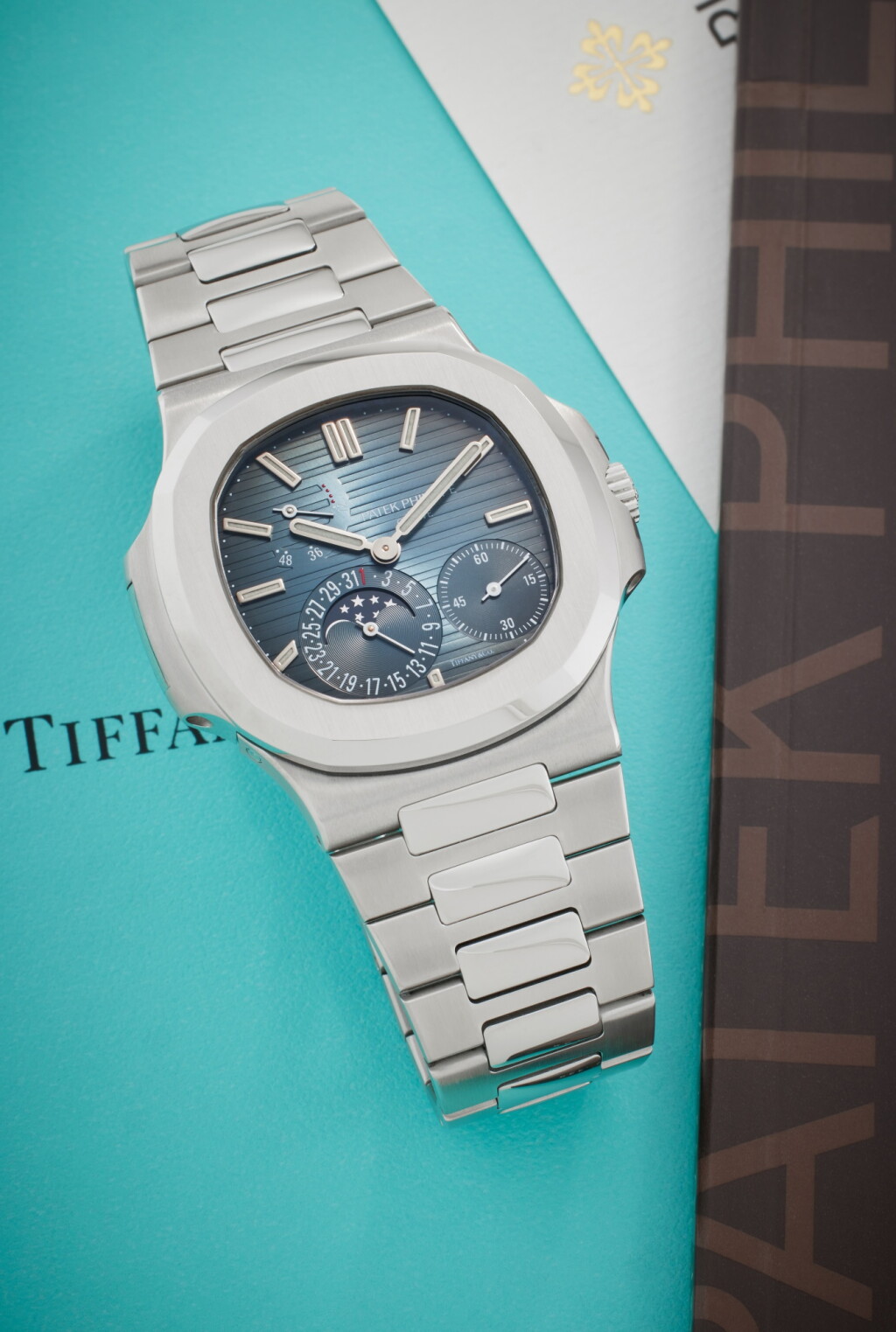 View full screen - View 1 of Lot 54. Reference 5712/1A-001 Nautilus | Retailed by Tiffany & Co.: A stainless steel automatic wristwatch with date, moon phases, power reserve indication, and bracelet, Circa 2012.