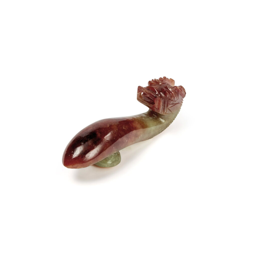 View full screen - View 1 of Lot 660. A red jadeite 'dragon' belt hook, Late Qing dynasty | 清末 翡玉雕龍首帶鉤.