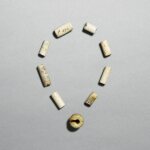 A celadon jade pendant, jue, Neolithic period, Hongshan culture, and eight jade beads, Neolithic period, Liangzhu culture | 新石器時代 紅山文化 青玉玦 及 良渚文化 玉管 一組九件