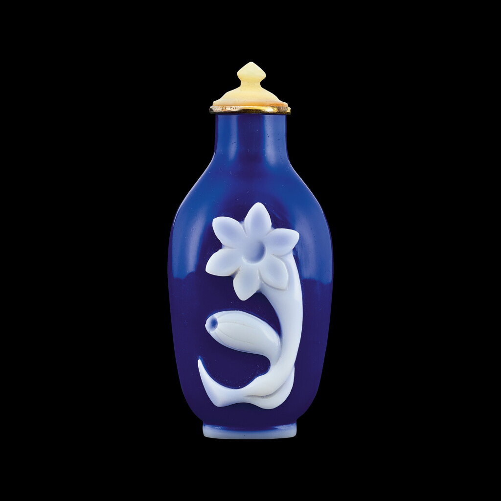 View full screen - View 1 of Lot 1001. A white overlay cobalt-blue glass 'lily' snuff bottle Qing dynasty, 18th - 19th century | 清十八至十九世紀 藍地套白料萱花紋鼻煙壺.