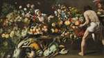 An interior with an array of fruits, vegetables and flowers arranged across a stone ledge, with a woman and two men