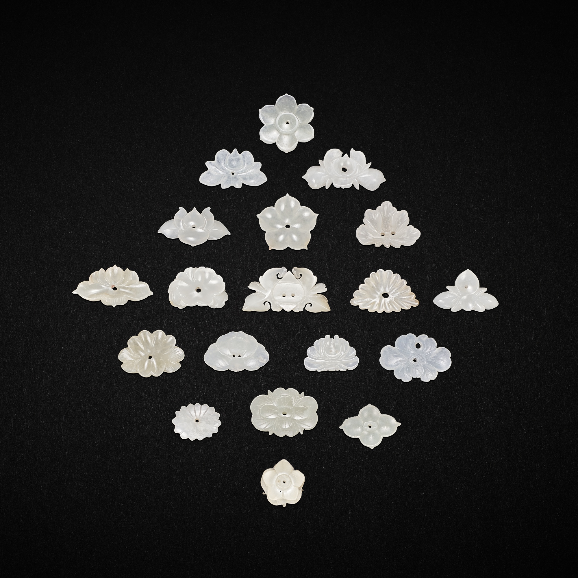 A group of thirty four white and pale celadon jade flower ornaments, Yuan Qing dynasty 元至清
